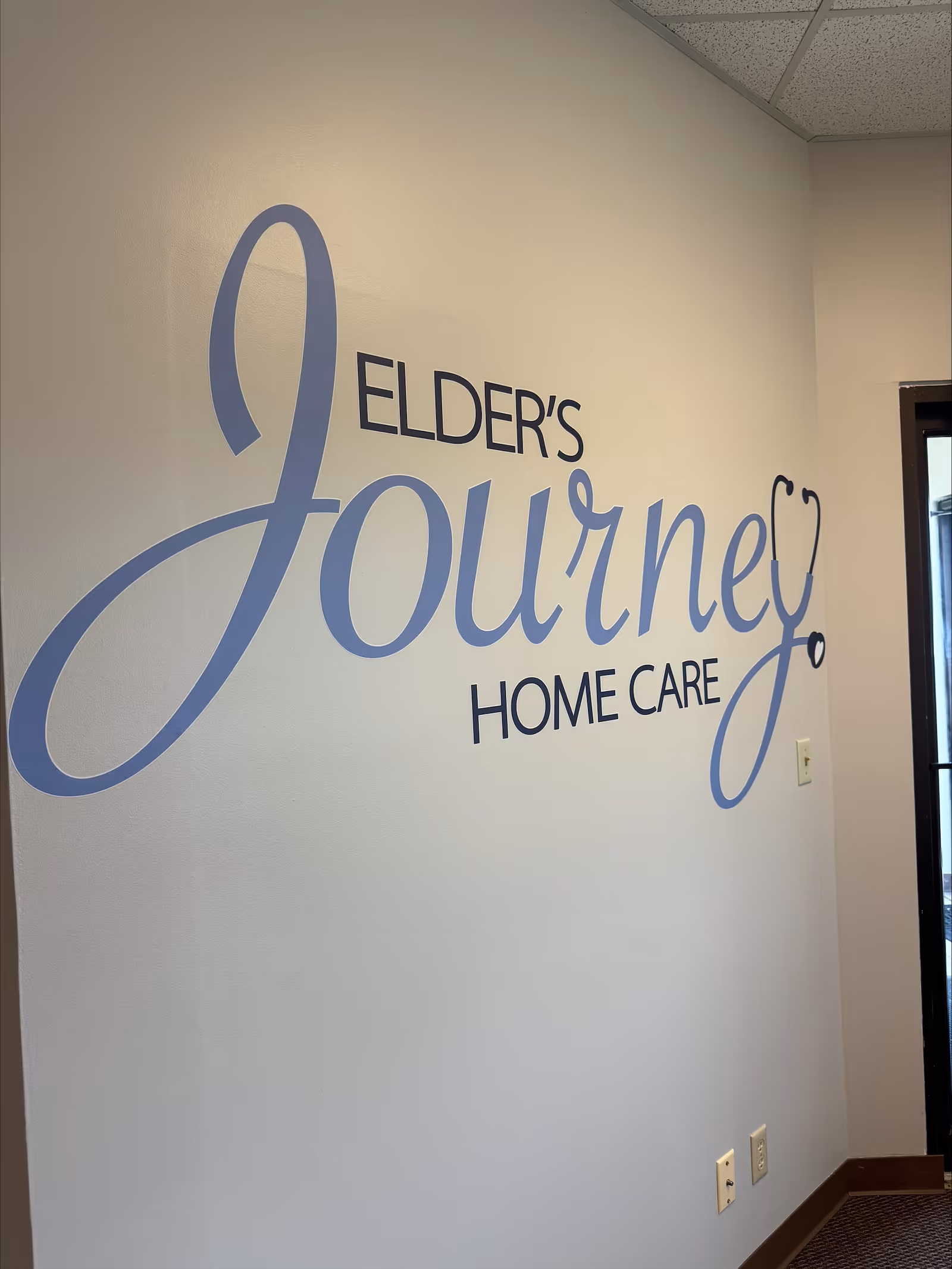 Interior wall featuring a large Elder's Journey Home Care sign and doorway.
