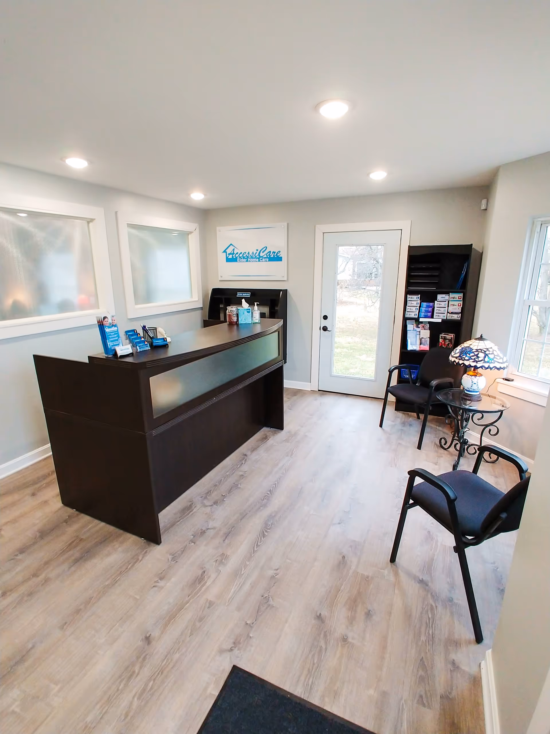 Reception area with a dark wood front desk, sign, and waiting chairs.