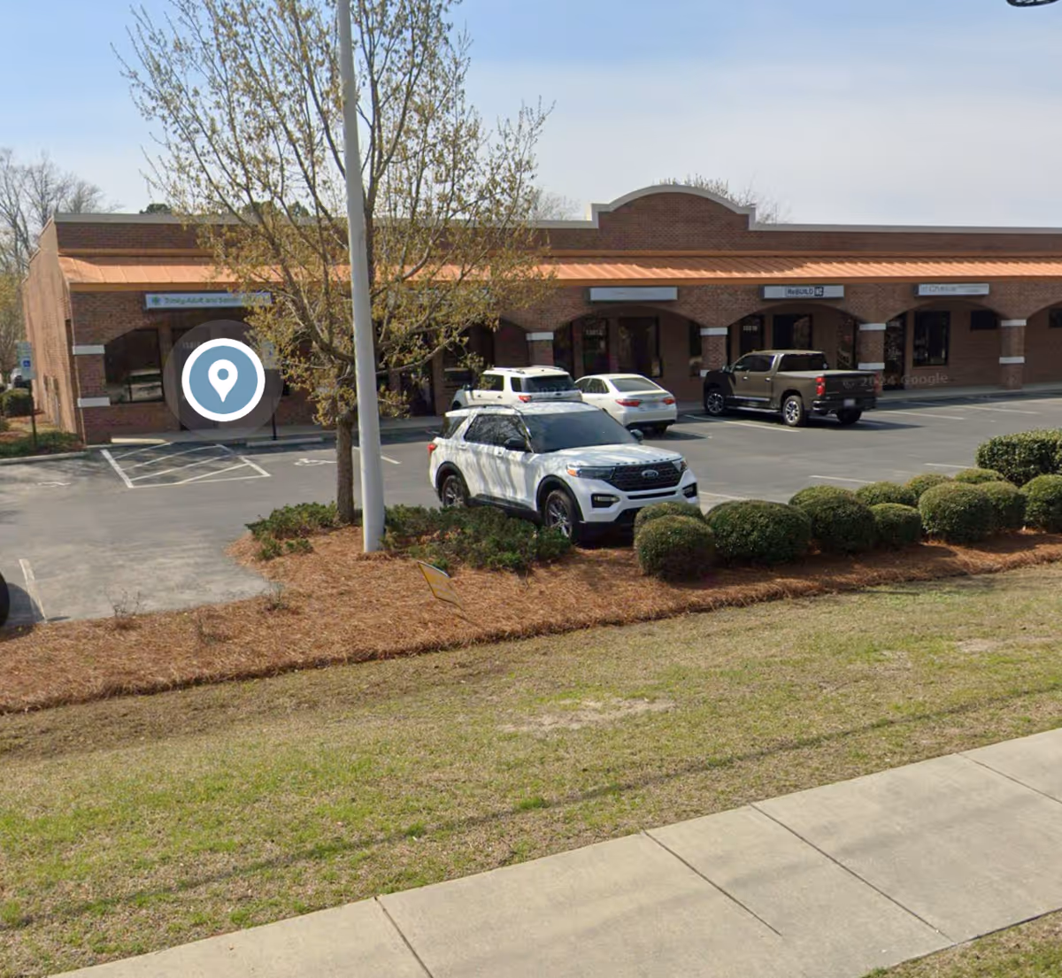 Brick storefront of Trinity Adult and Senior Services LLC with parked cars.