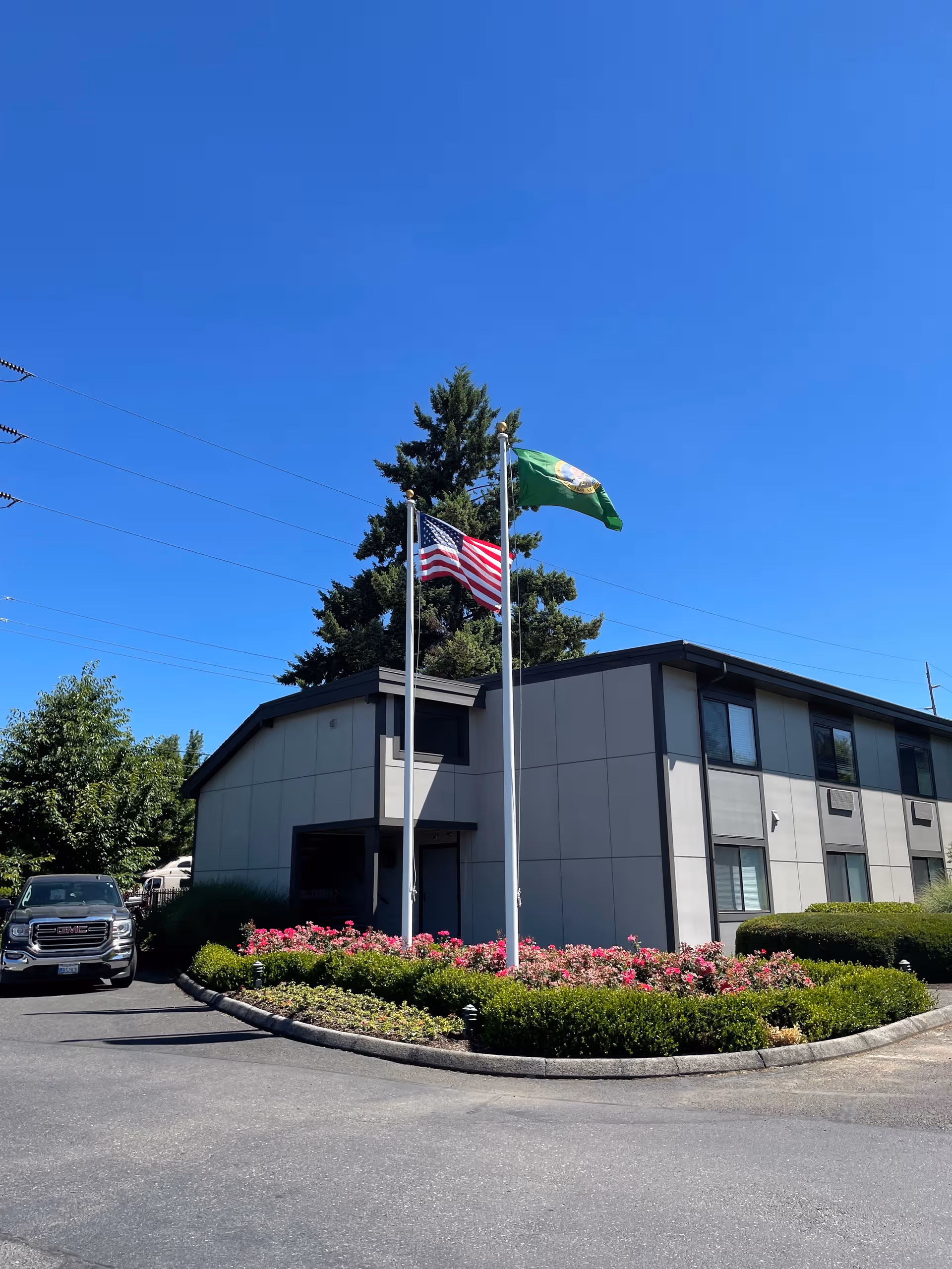 Front exterior of Cascade Inn Assisted Living Community with flagpoles and landscaped entrance.