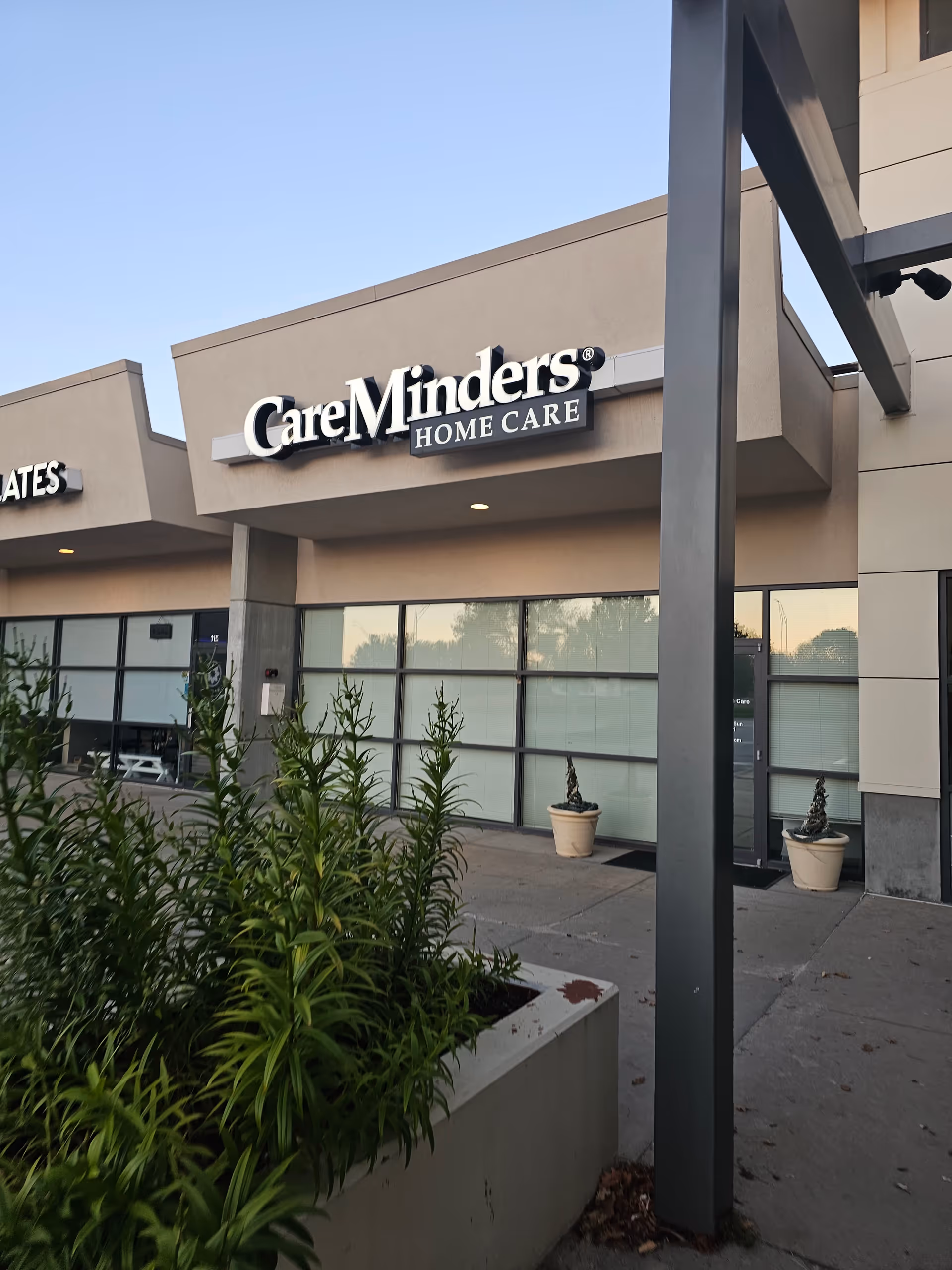This is an exterior view of the CareMinders Home Care building with entrance and potted plants.