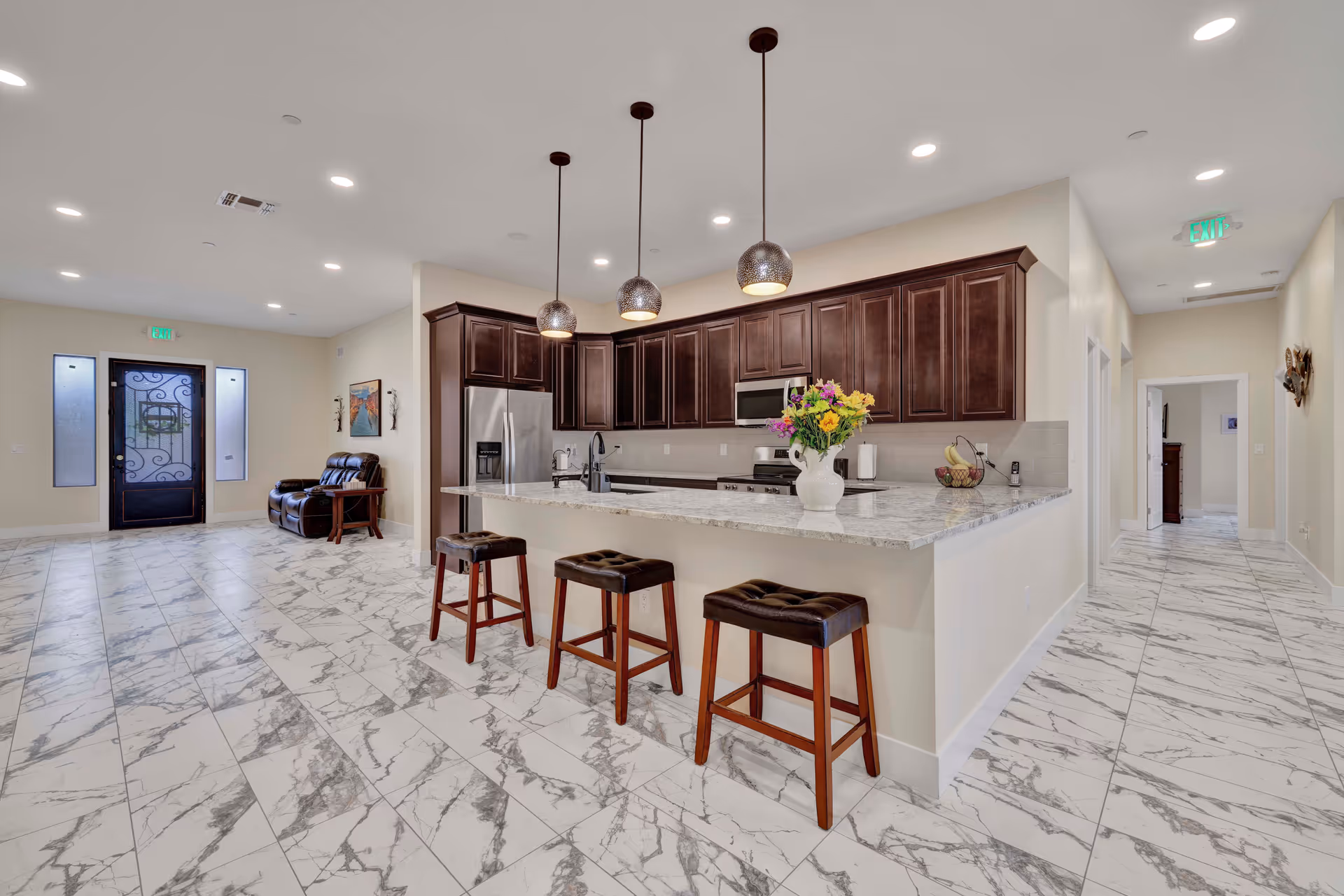 Bright modern kitchen with marble floor, dark cabinets, and a breakfast bar.