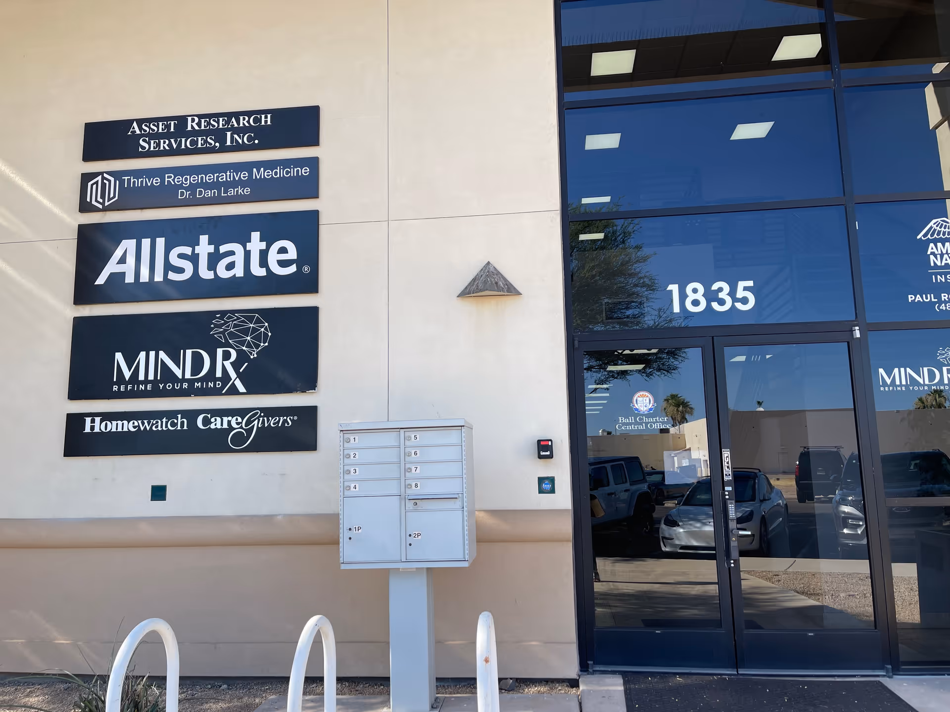 Exterior building front with multiple business signs and glass entry doors.