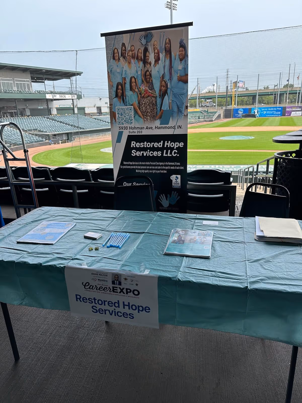 Outdoor expo booth and banner for Restored Hope Services LLC at a baseball stadium.