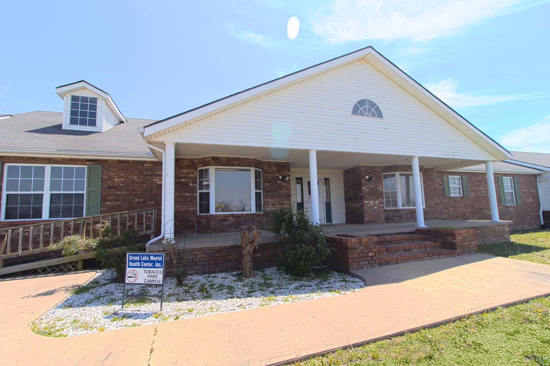 Exterior of a brick residential facility with white porch, columns, and front entrance.