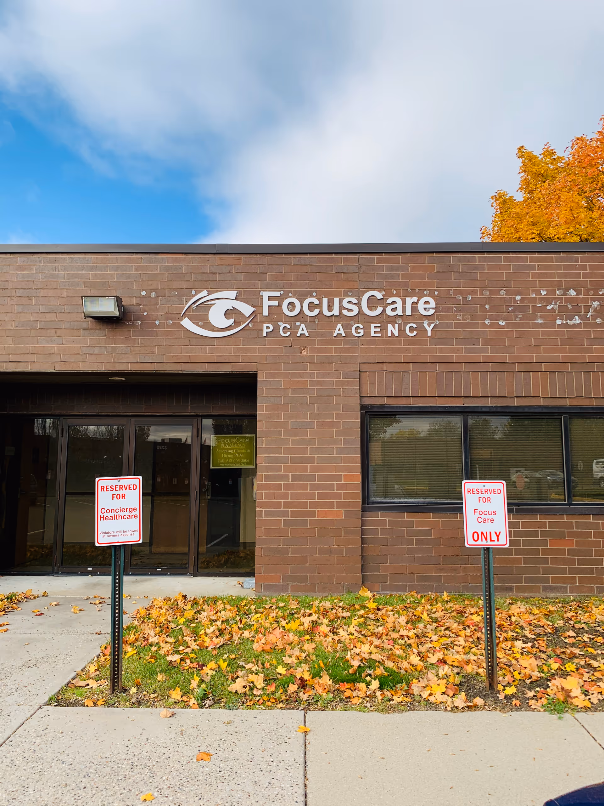 Brick building facade with FocusCare PCA Agency sign and autumn leaves in front.