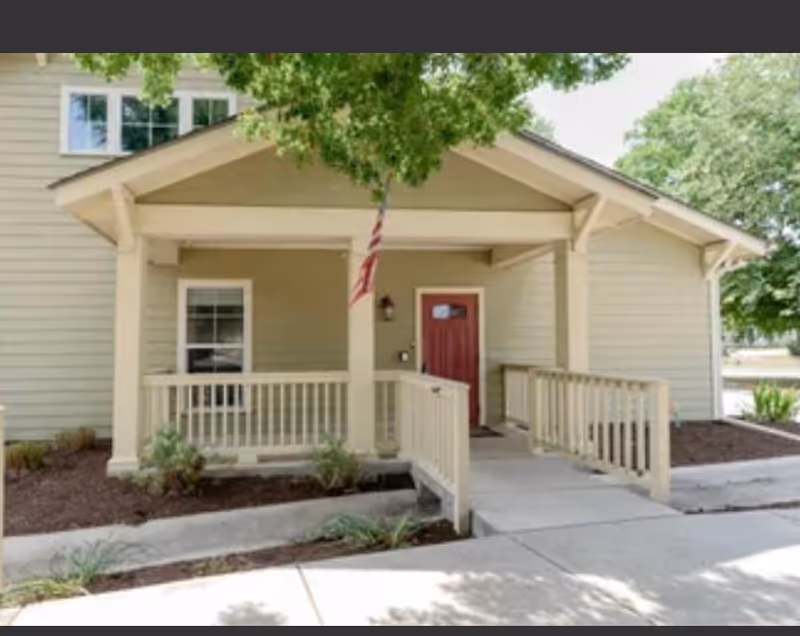 Front view of Acclaimed Senior Living facility entrance with porch and red door