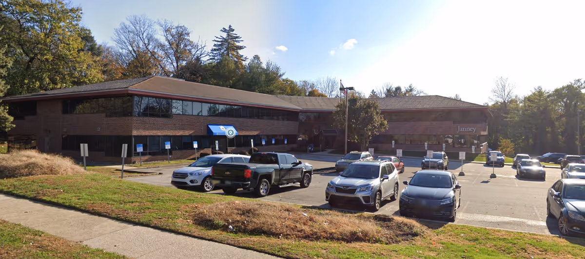 Brick senior care building with blue awnings and a parking lot in front.