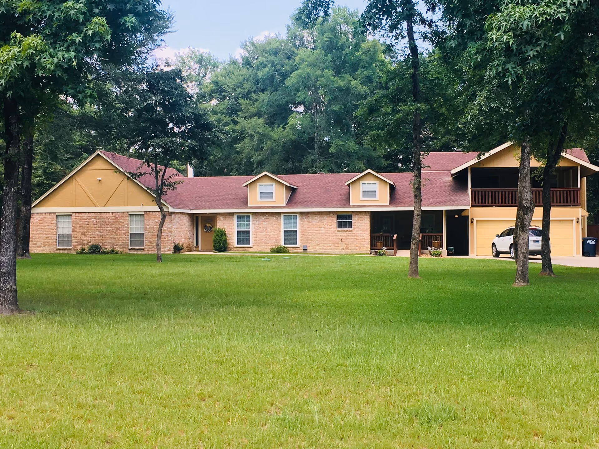 Brick senior living facility exterior with a red roof and green lawn.
