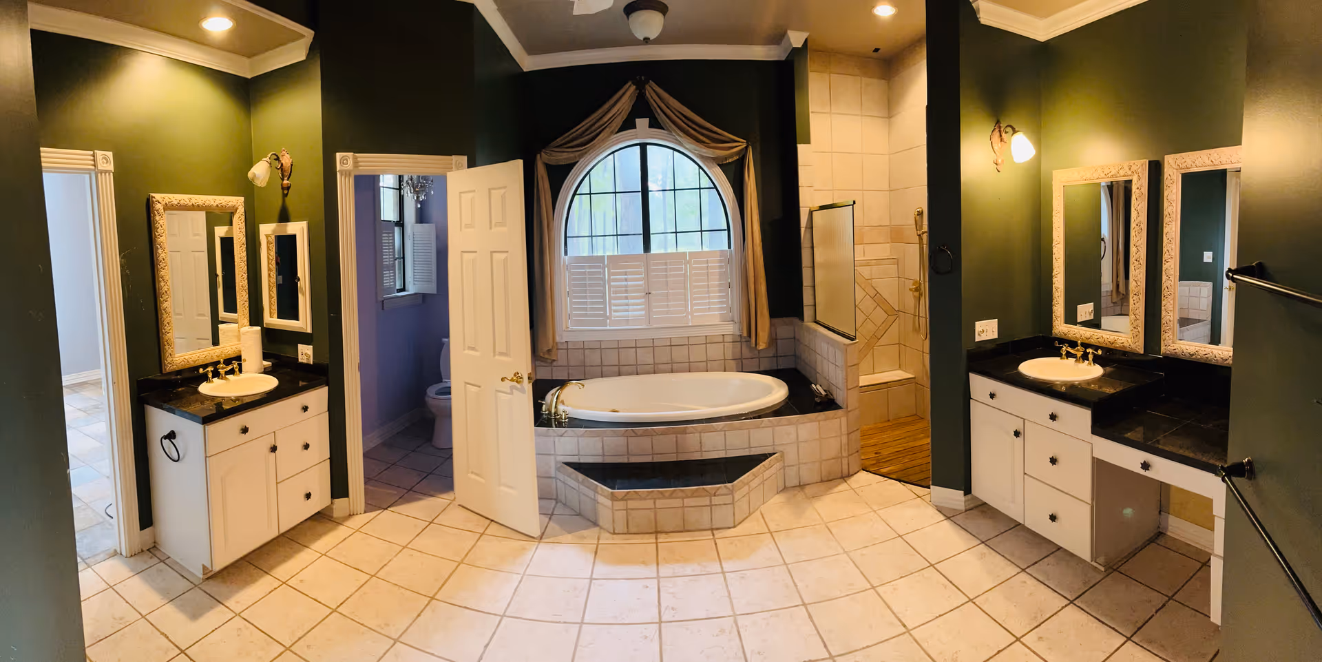 Large bathroom with two vanities, central bathtub, walk-in shower, and green walls.