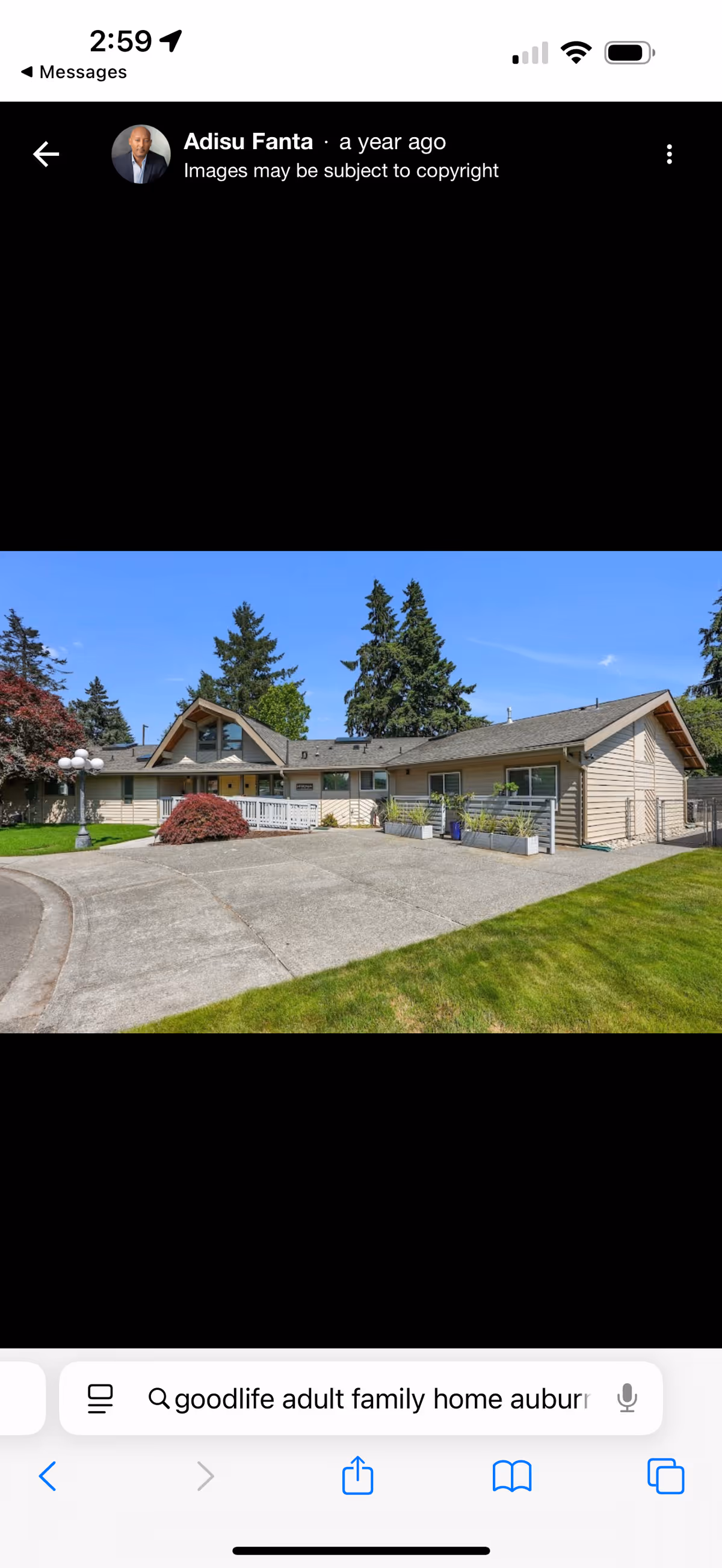 Single-story senior living facility with beige siding, front entrance, driveway, and surrounding trees.