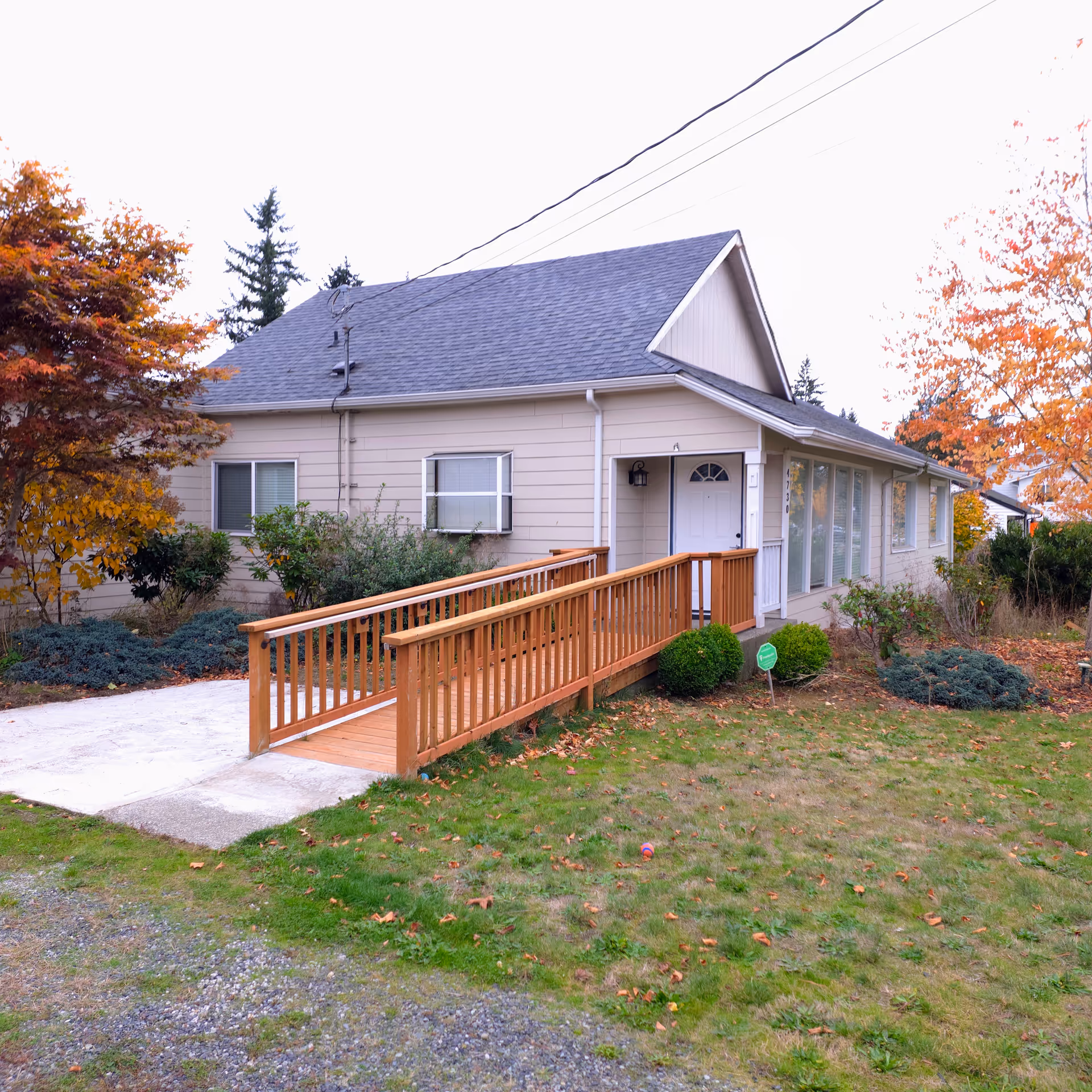 Front view of a single-story beige home with a wooden ramp.