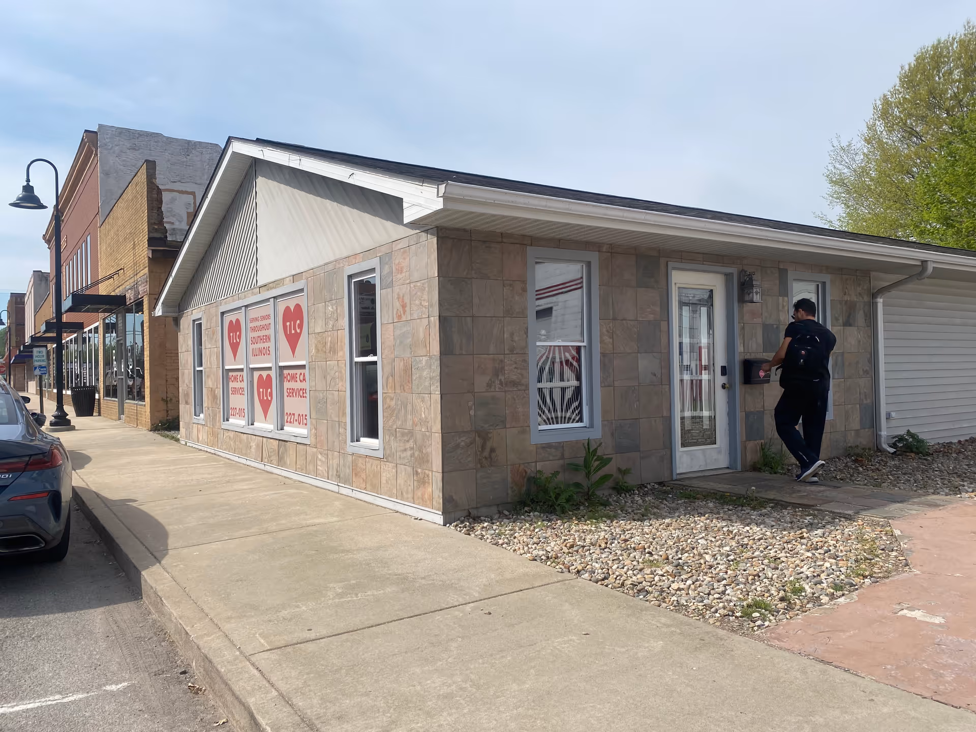 Single-story storefront with TLC Home Care Services signs; a man approaches the entrance.