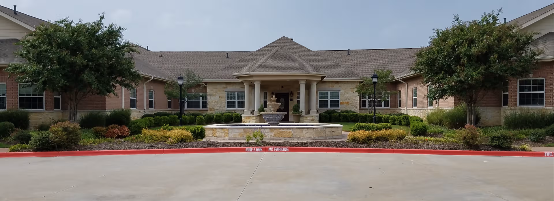 Front exterior of Colonial Oaks at Rockwall with central fountain and landscaped entrance