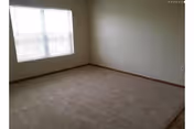 Unfurnished carpeted room with a window and beige walls in a senior facility.