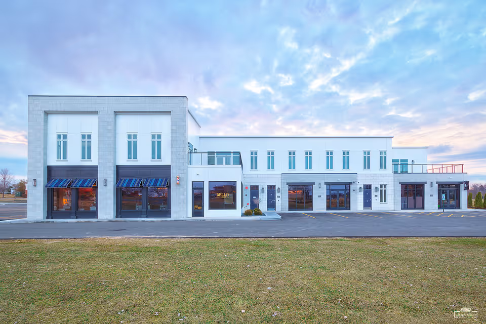 Modern two-story senior living facility exterior with large storefront windows and a curbside parking lot.