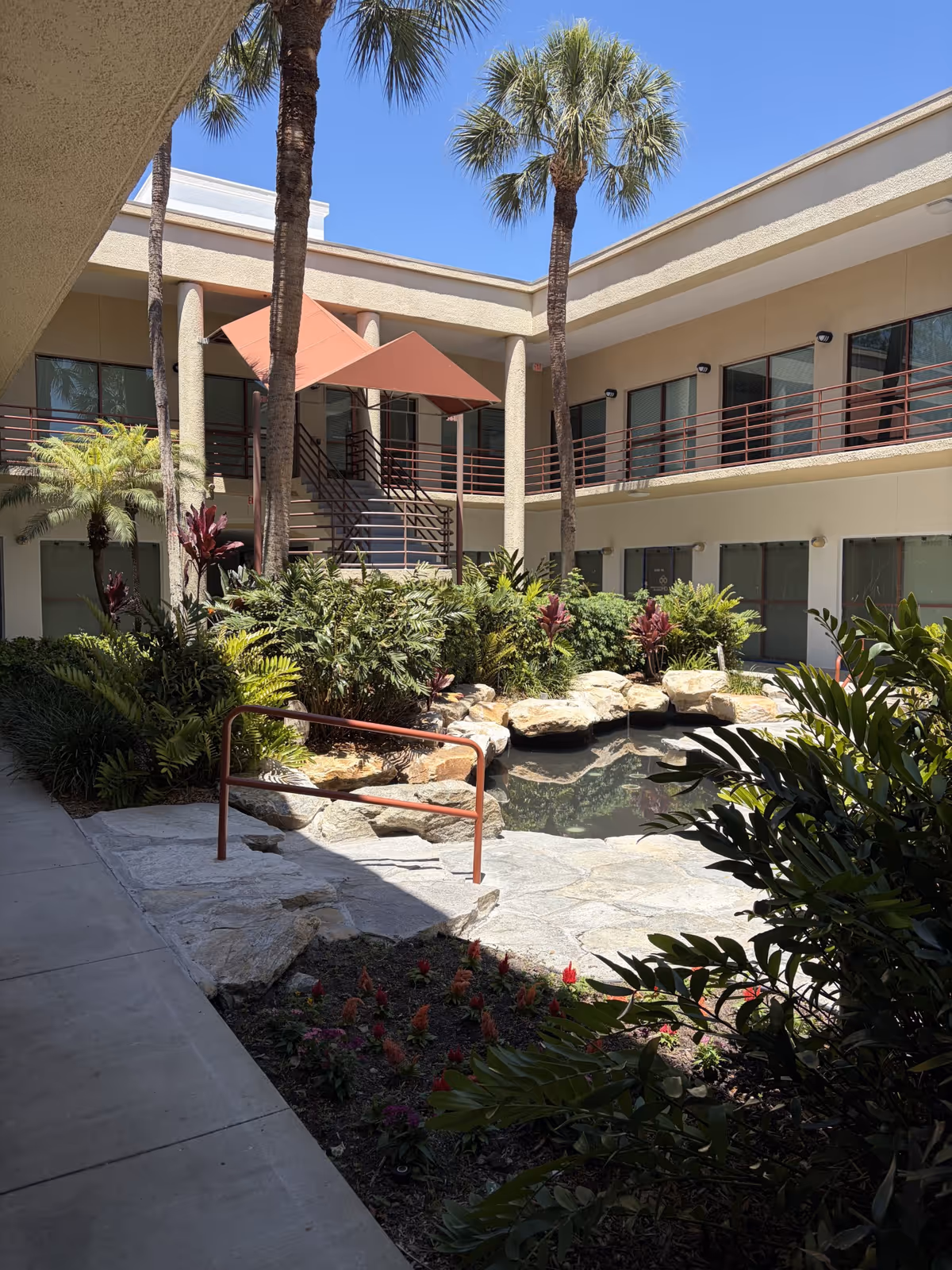 Outdoor courtyard at Interim HealthCare of Sarasota featuring a pond, rocks, and landscaping.