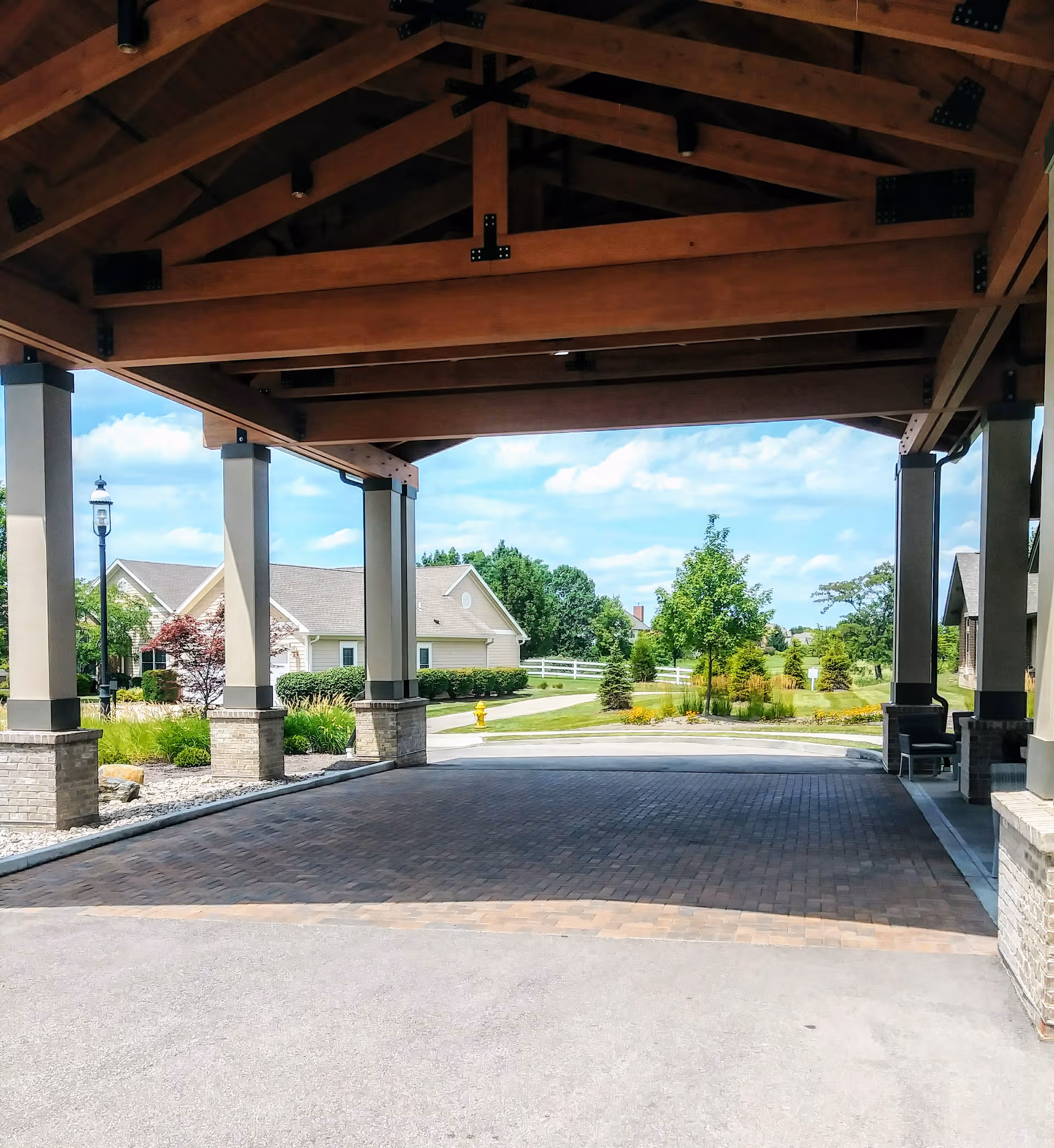 Covered entrance of Liberty Place Memory Care with wooden beams and brick-paver driveway.