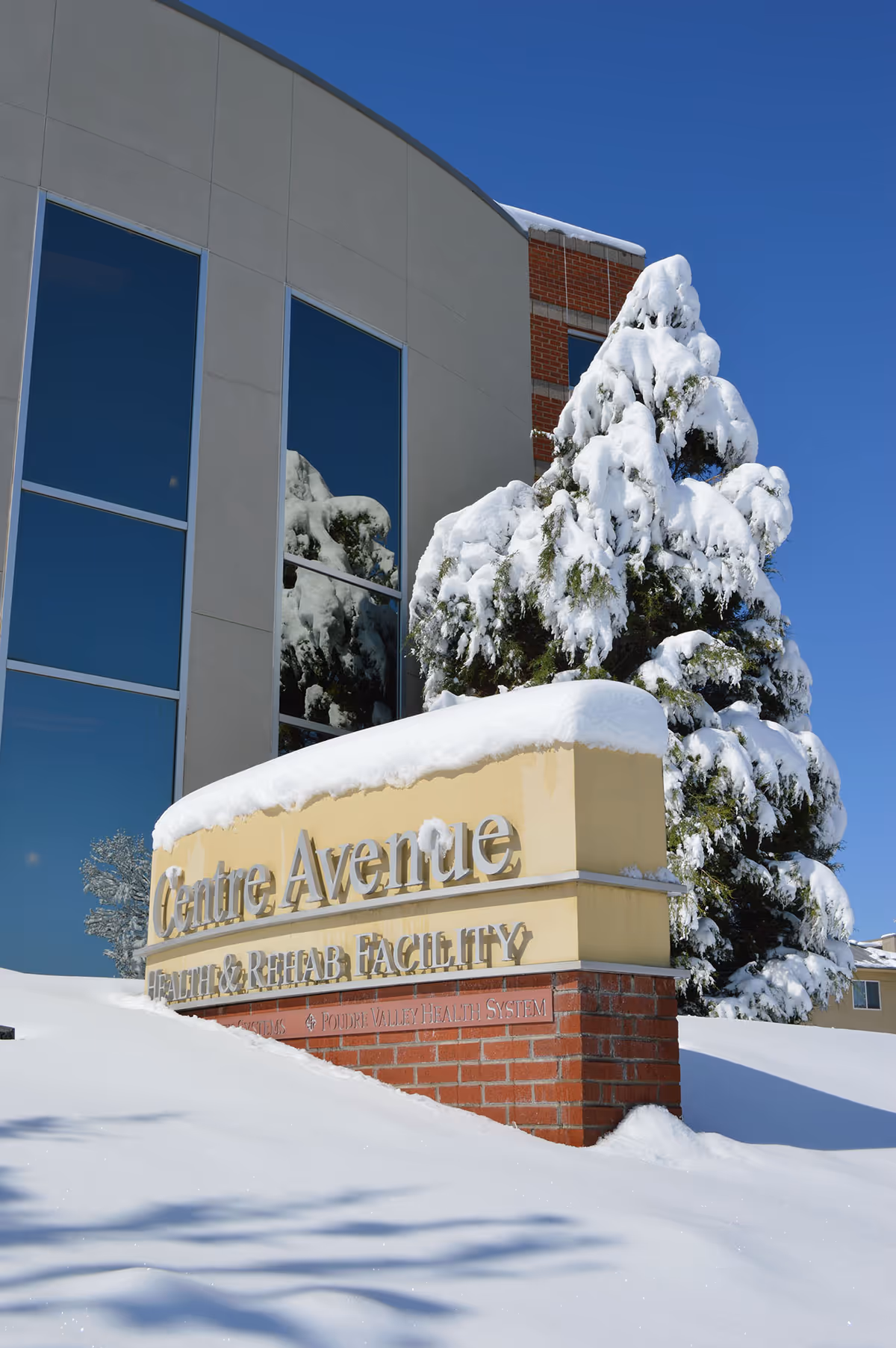 Snow covers the front of Centre Ave Health & Rehab building with a sign.