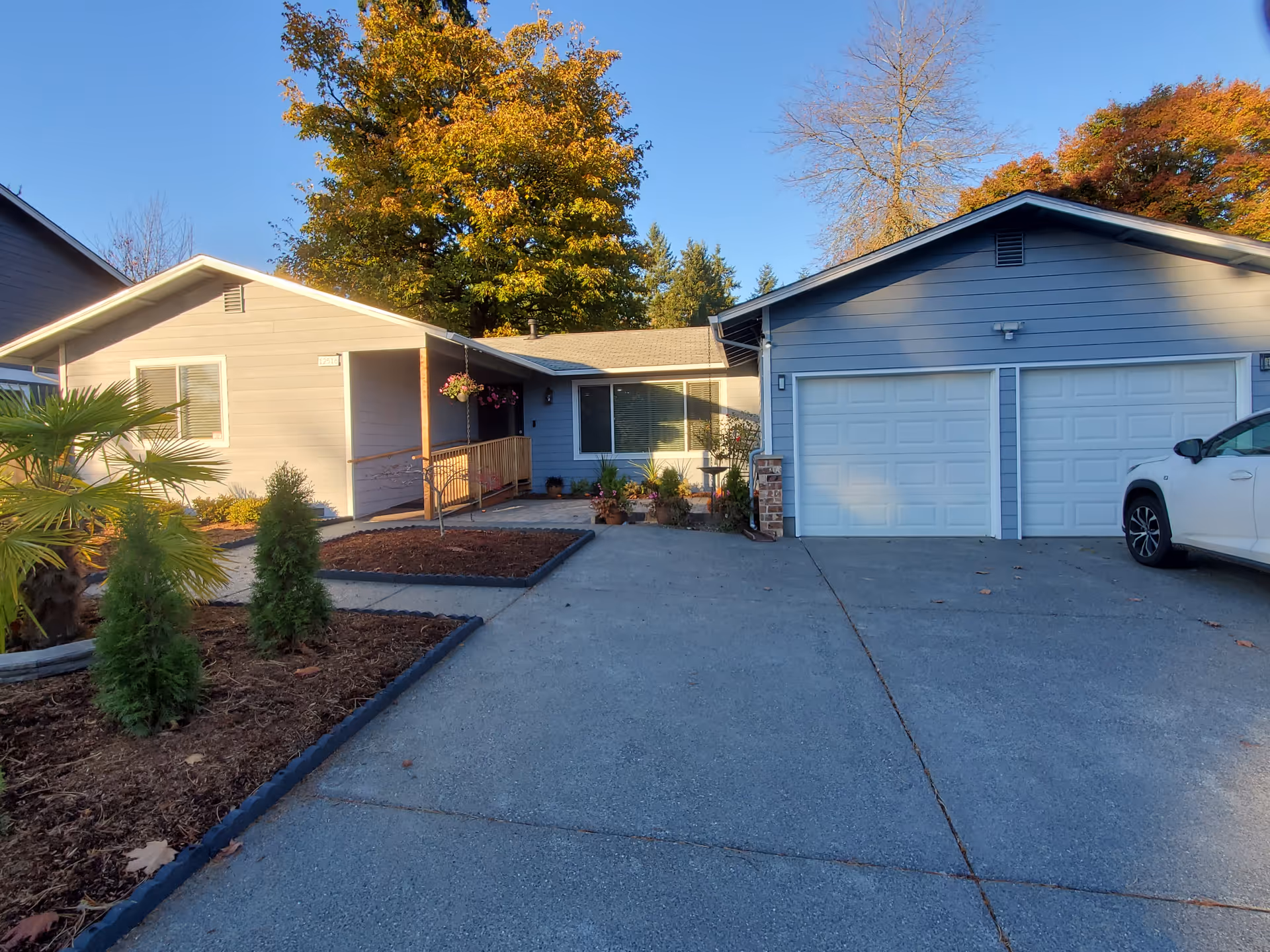 A single-story front exterior of a house with two garages, driveway, and landscaping.