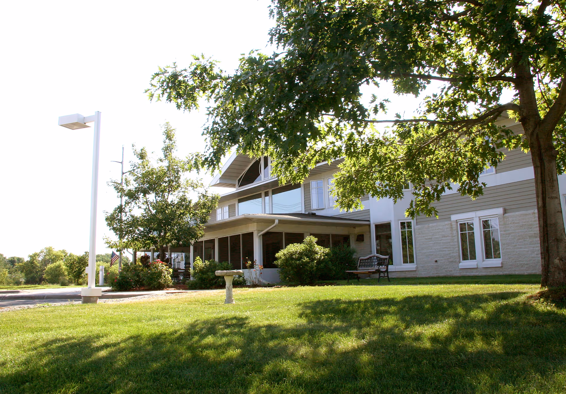 Exterior view of Country Manor Extended Service I with lawn, trees, and benches.
