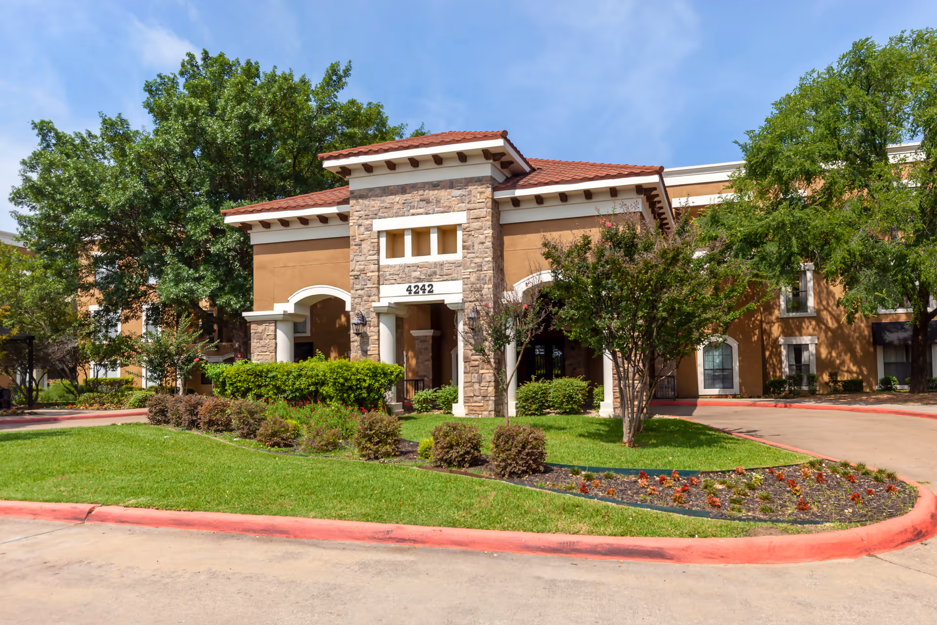 Exterior view of a senior living facility with stone entry and manicured landscaping.