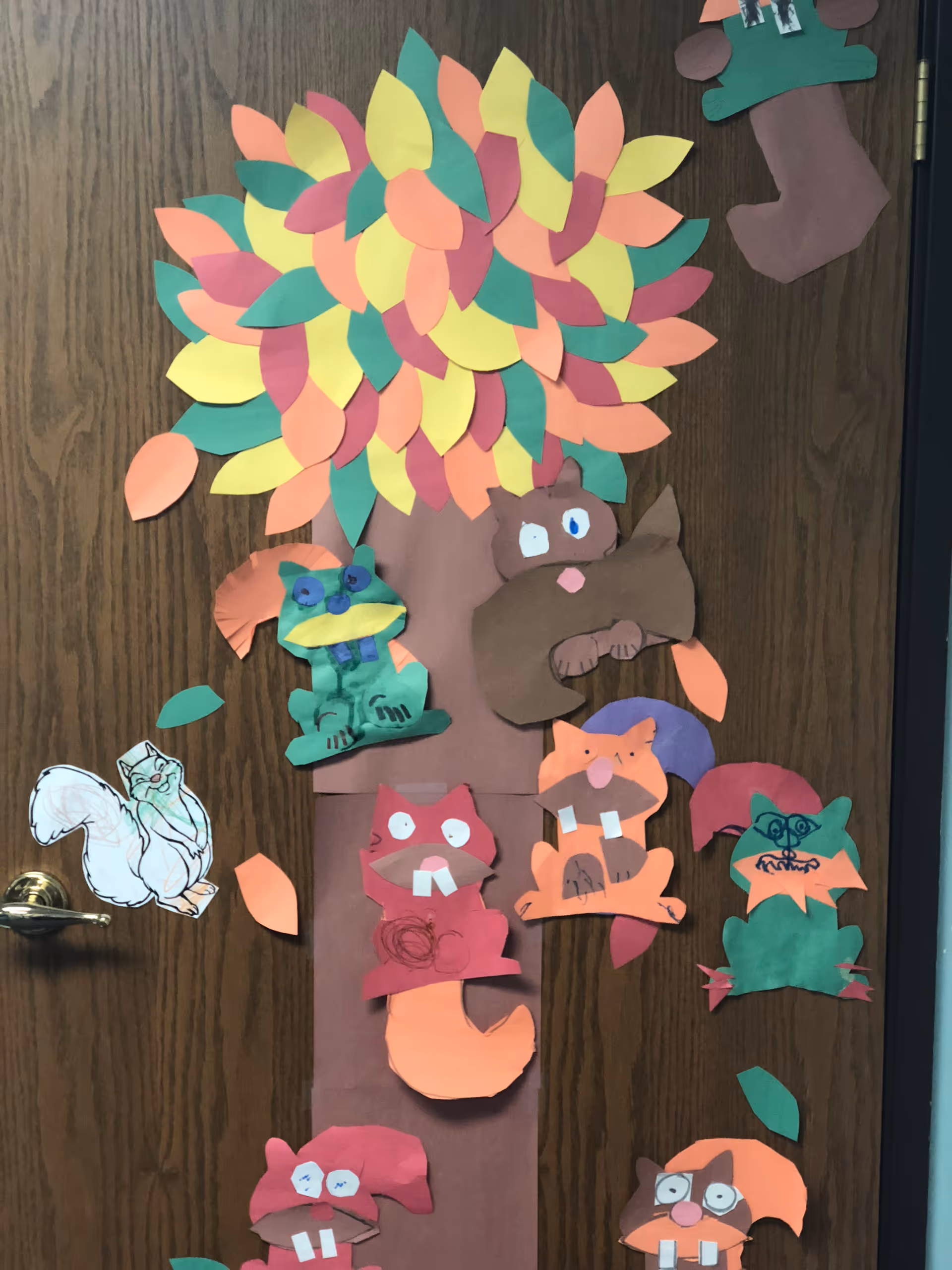Colorful paper tree with animal crafts attached to a wooden door.