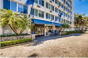 Exterior view of Hillcrest Hampton House with blue awnings, palm trees, and a paved entrance.