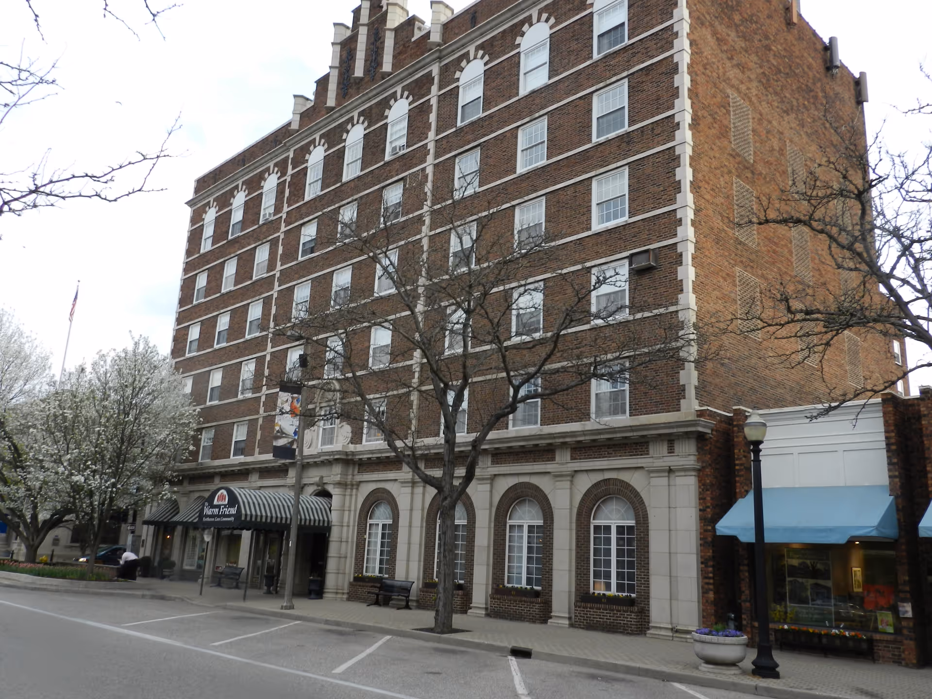 Brick, multi-story building with The Warm Friend storefront along a city street.