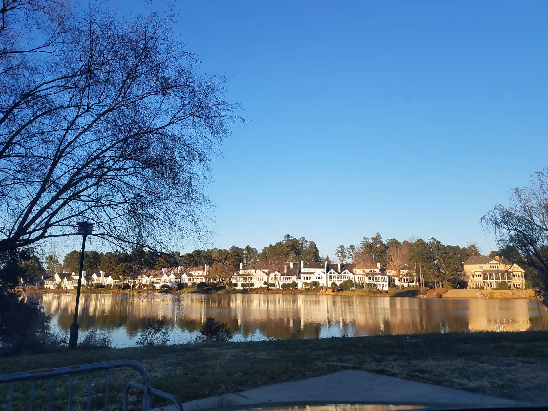 Willow Creek Senior Living Apartments across a calm lake with houses and trees.