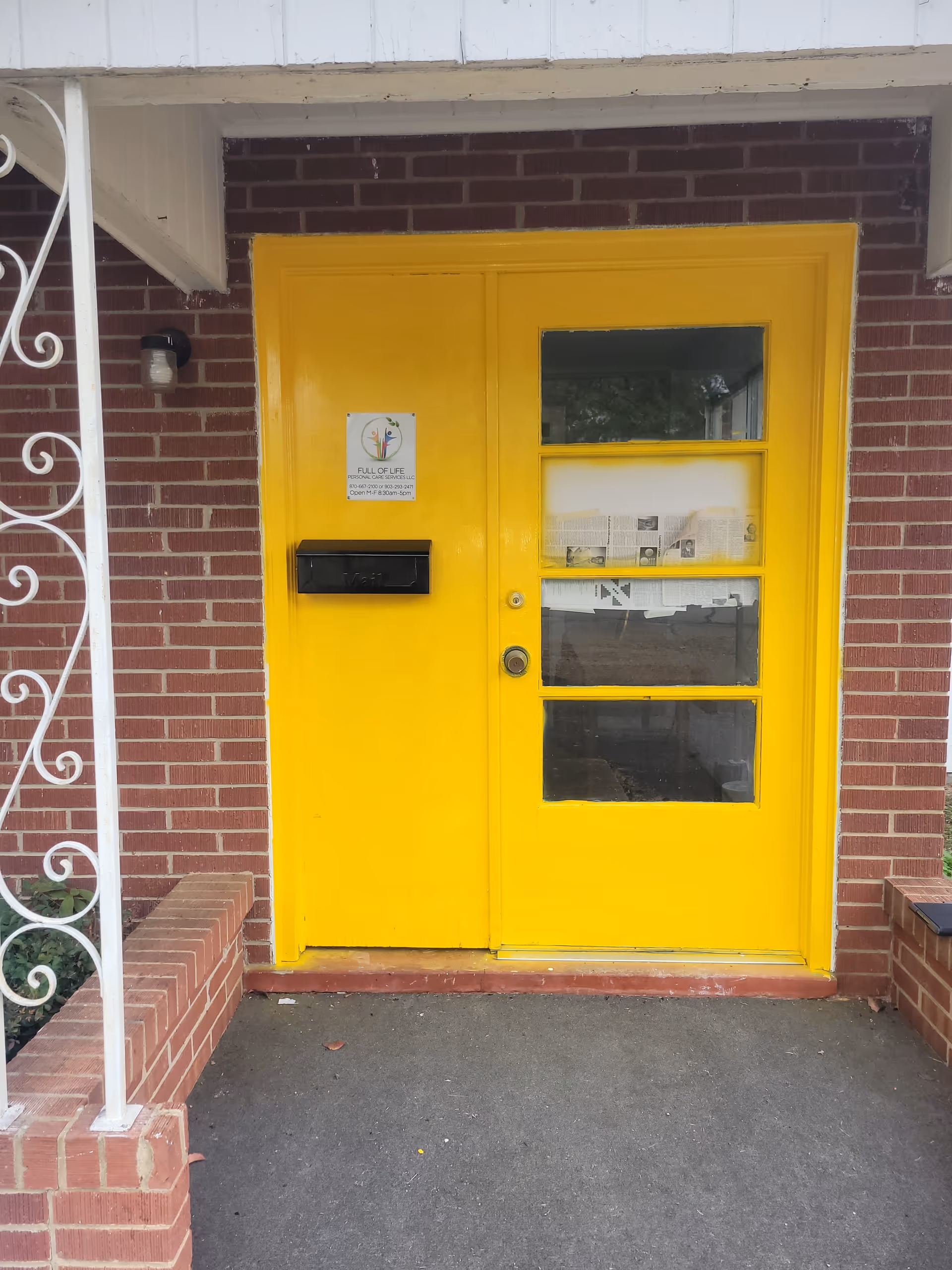 Bright yellow front doors with brick exterior at a senior care facility entrance.