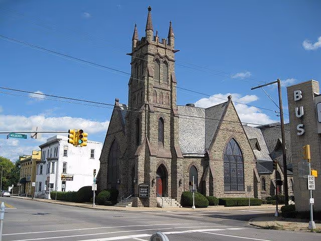 Gothic stone church on a street corner with traffic signals.