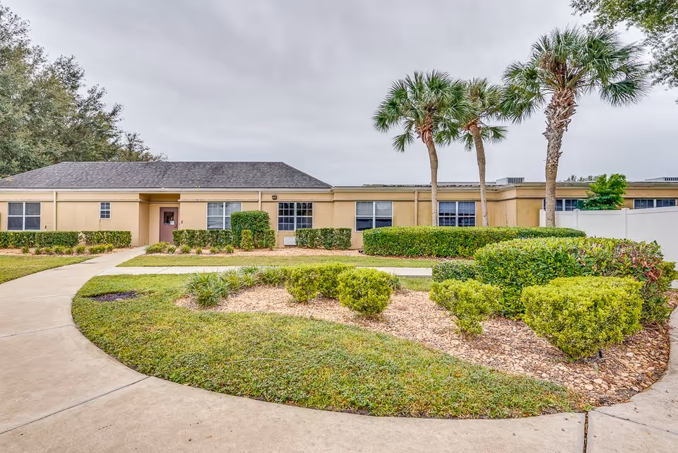Front exterior of Pacifica Senior Living Ocala with landscaping and palm trees.