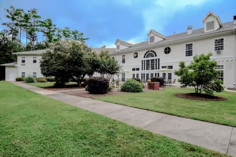 Wesley Village Senior Living building exterior with a green lawn, trees, and curved walkway.