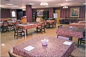 A dining room with purple-patterned tablecloths, empty tables, and chandeliers.