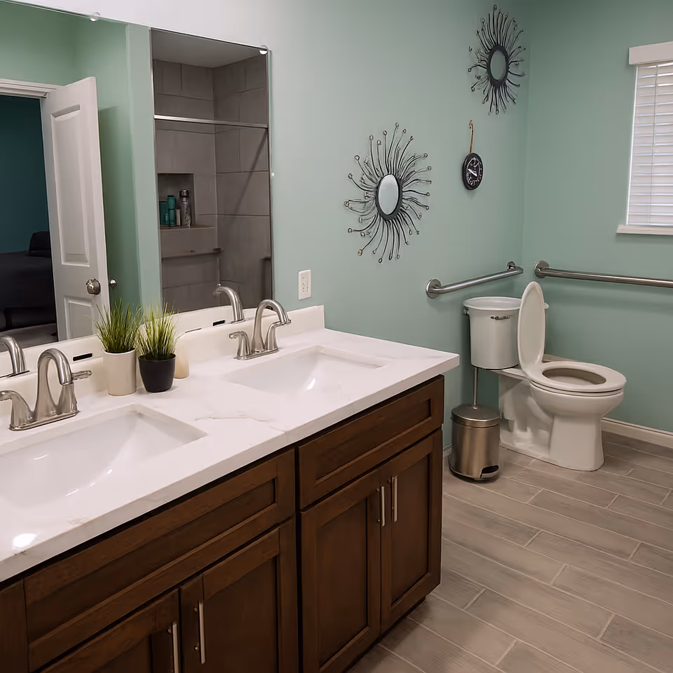 Two-sink bathroom vanity with marble countertop, large mirror, teal walls, and a toilet.