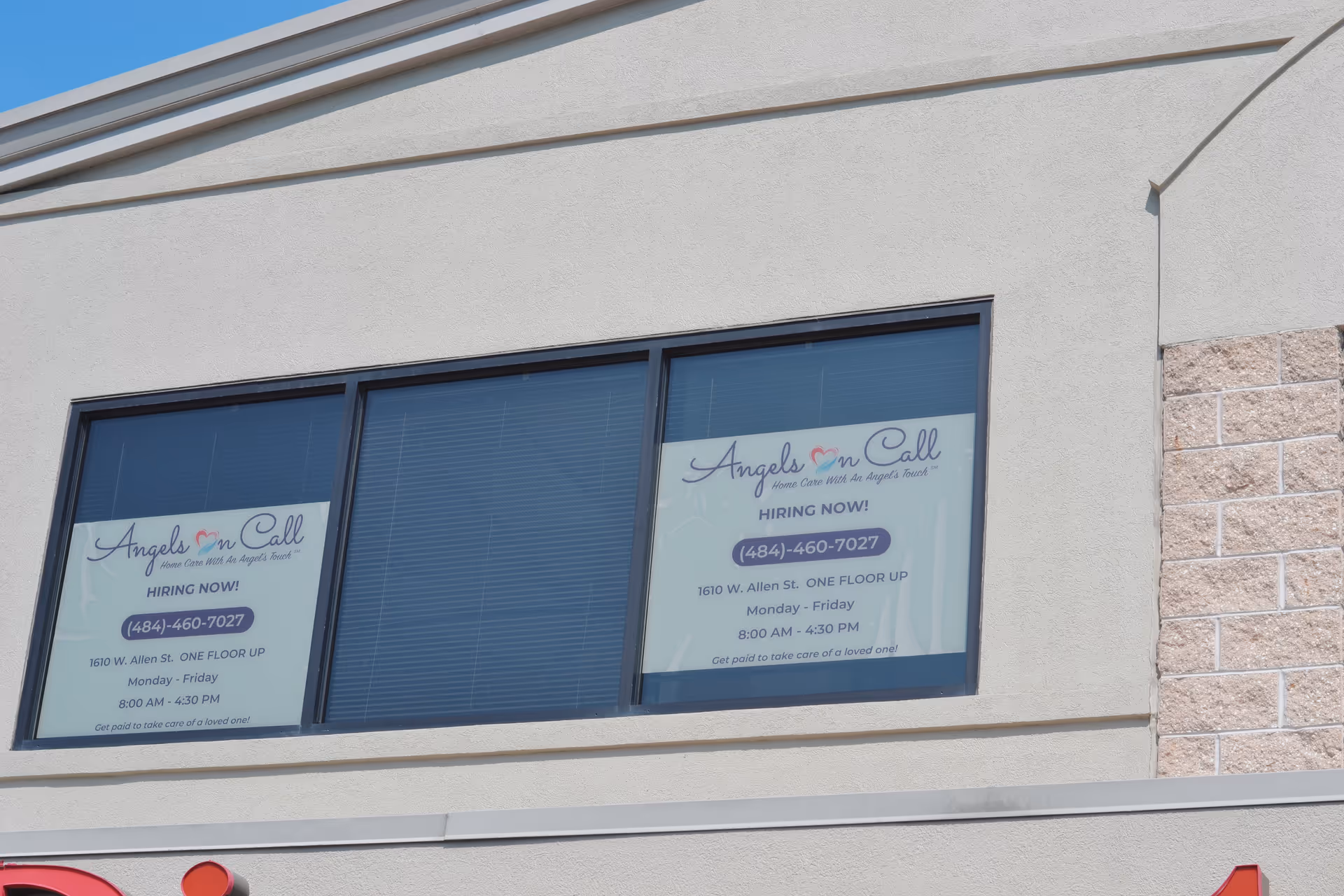 Exterior of a building with two windows showing Angels On Call hiring signs.