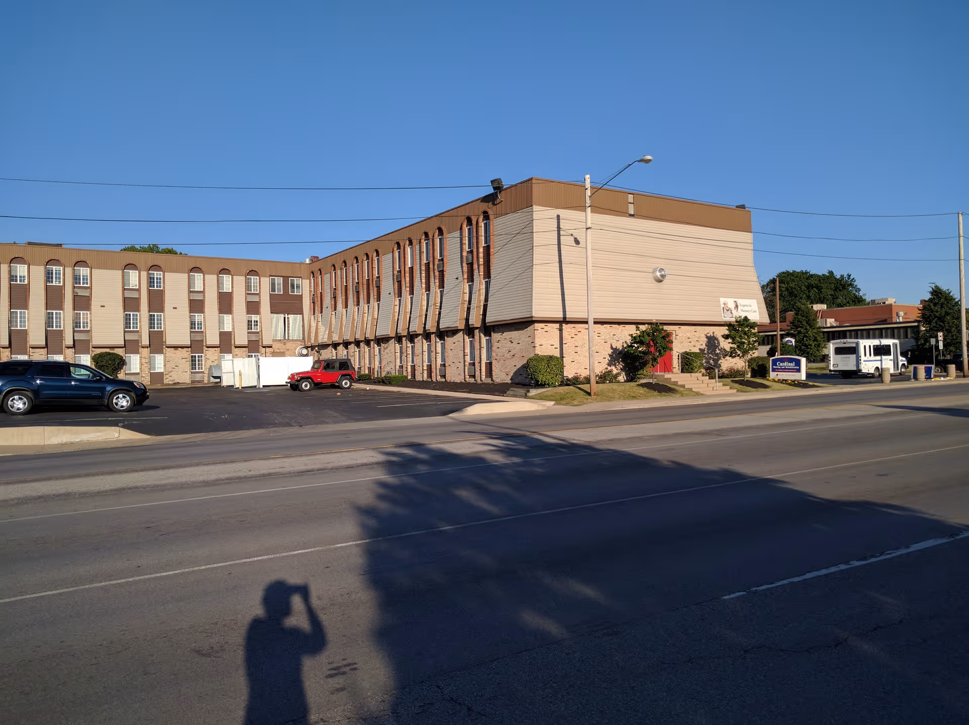 Exterior view of Cardinal Nursing and Rehabilitation building along a street, with parked cars.