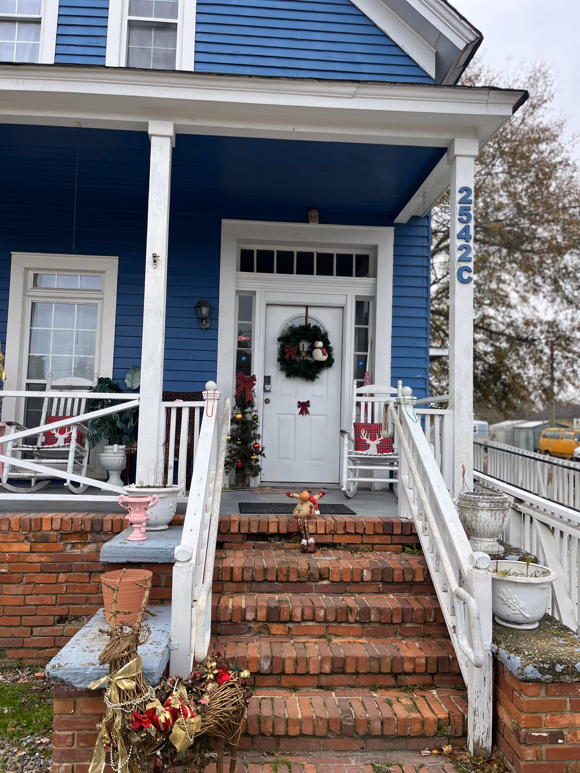 Blue two-story building with white trim, brick front steps, and Christmas decorations.