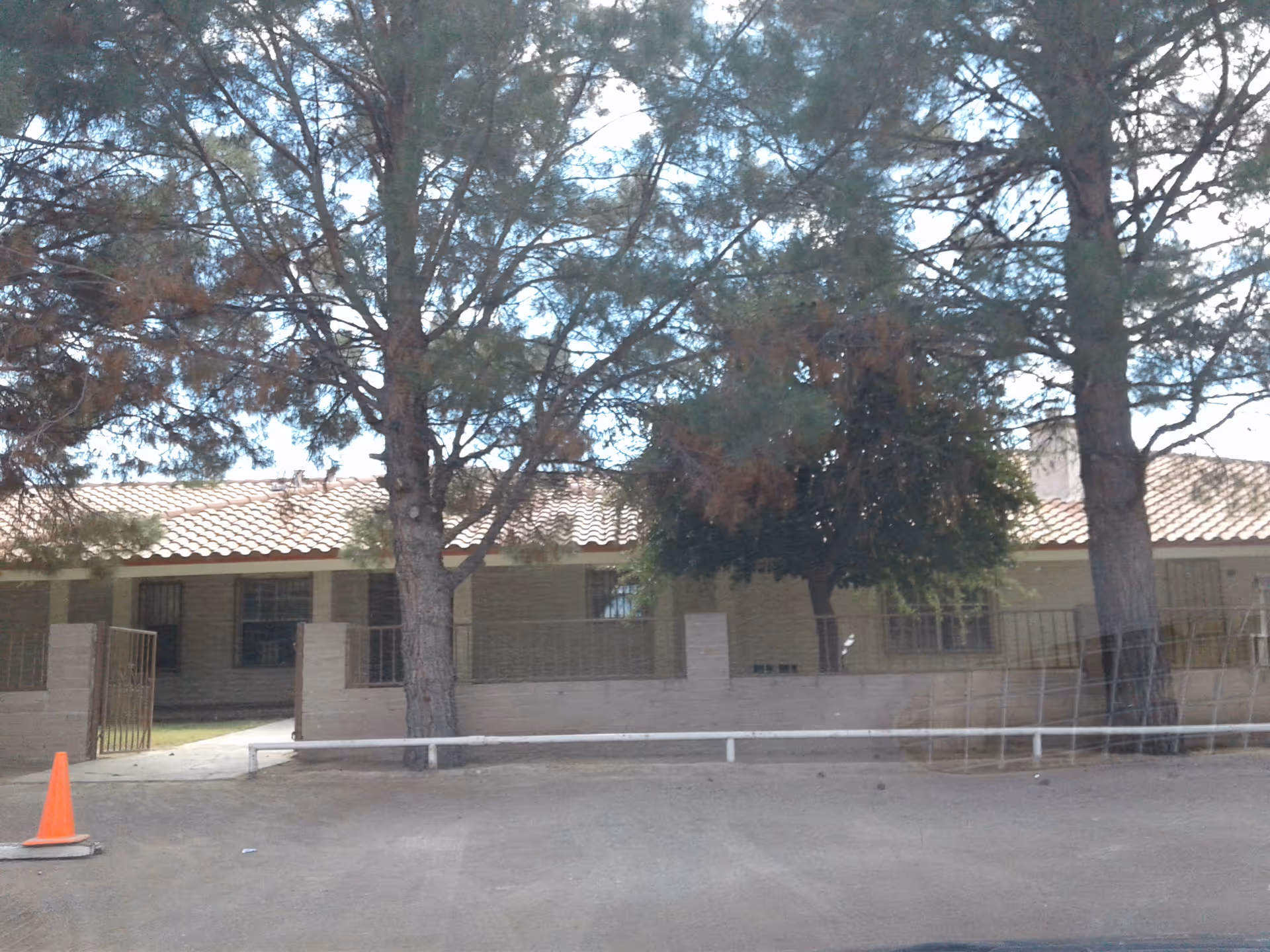 Exterior view of a single-story senior living facility with trees and brick frontage.