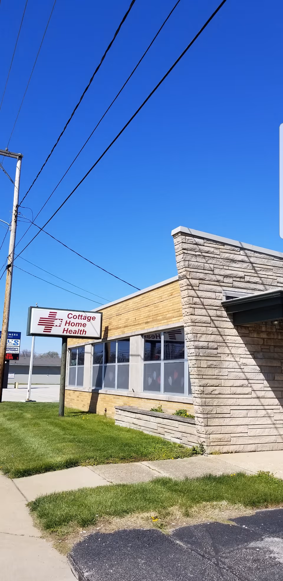 Exterior view of Cottage Home Health building with sign, windows, and blue sky.