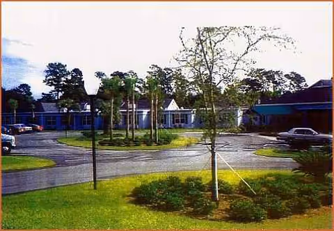 Exterior view of Pacifica Senior Living Ocala showing the building front, parking, and trees.
