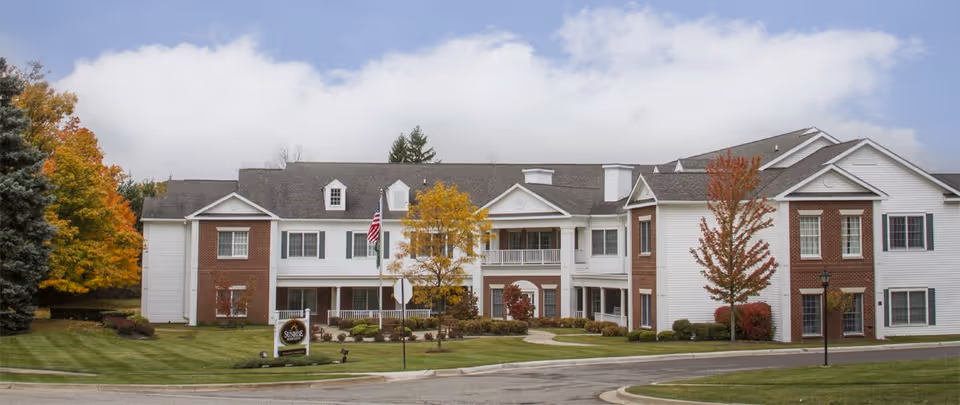 Exterior view of a Fairmont of Farmington Hills senior living building with manicured lawn and trees.
