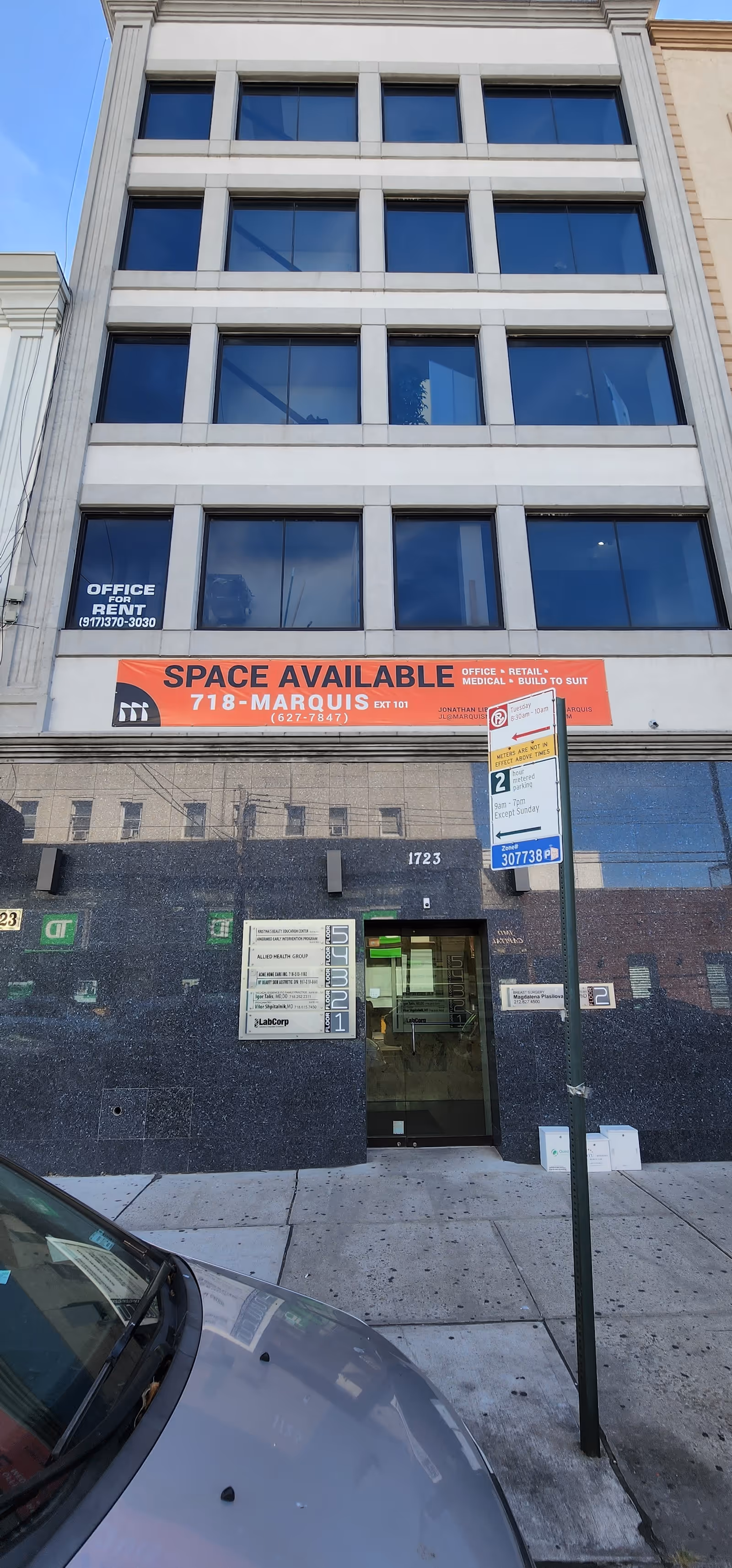 Tall urban building facade with large windows and a Space Available banner.