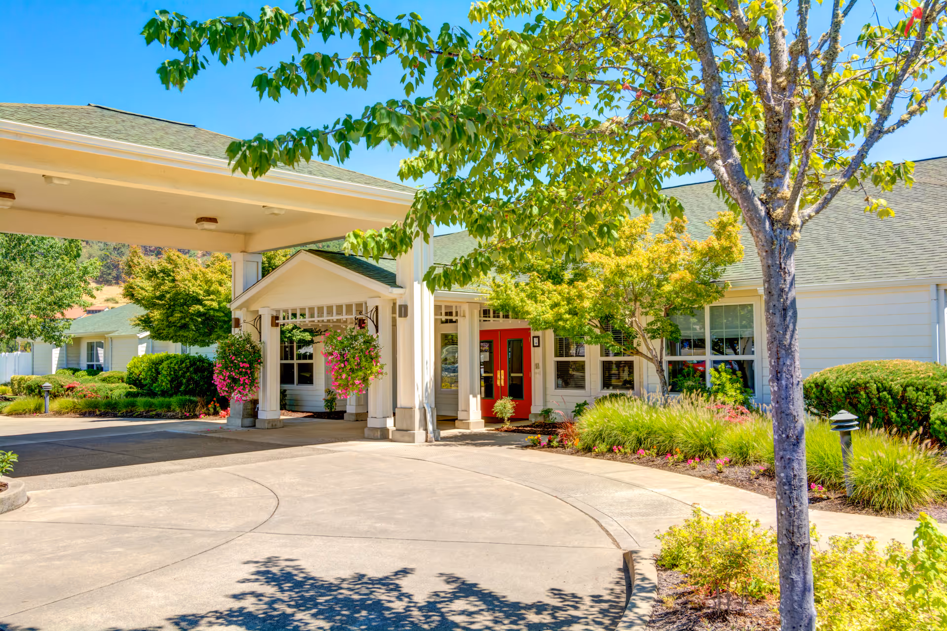 Front entrance of Callahan Court Memory Care showing a covered porte-cochere, red double doors, and landscaped grounds.