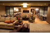 A spacious lounge and dining area with sofas, tables, and warm lighting.