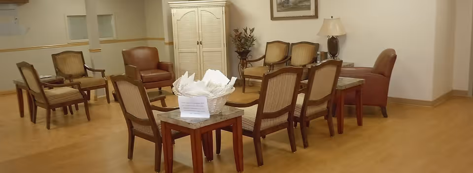 A communal seating area with multiple armchairs and side tables arranged on a wood floor and a basket on a center table.