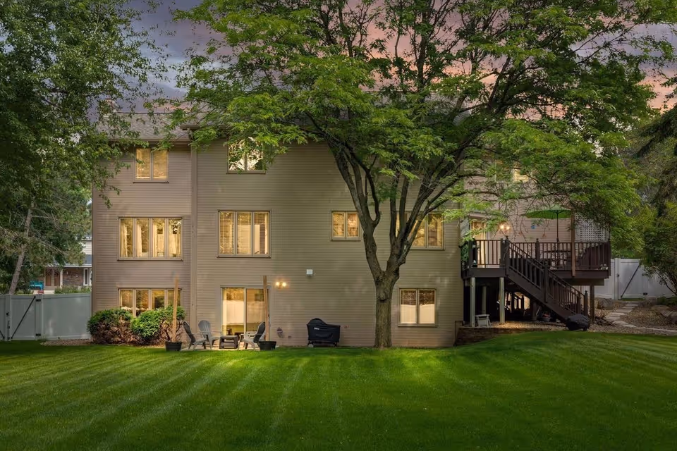 Exterior view of a two-story beige building with a deck and lush lawn.