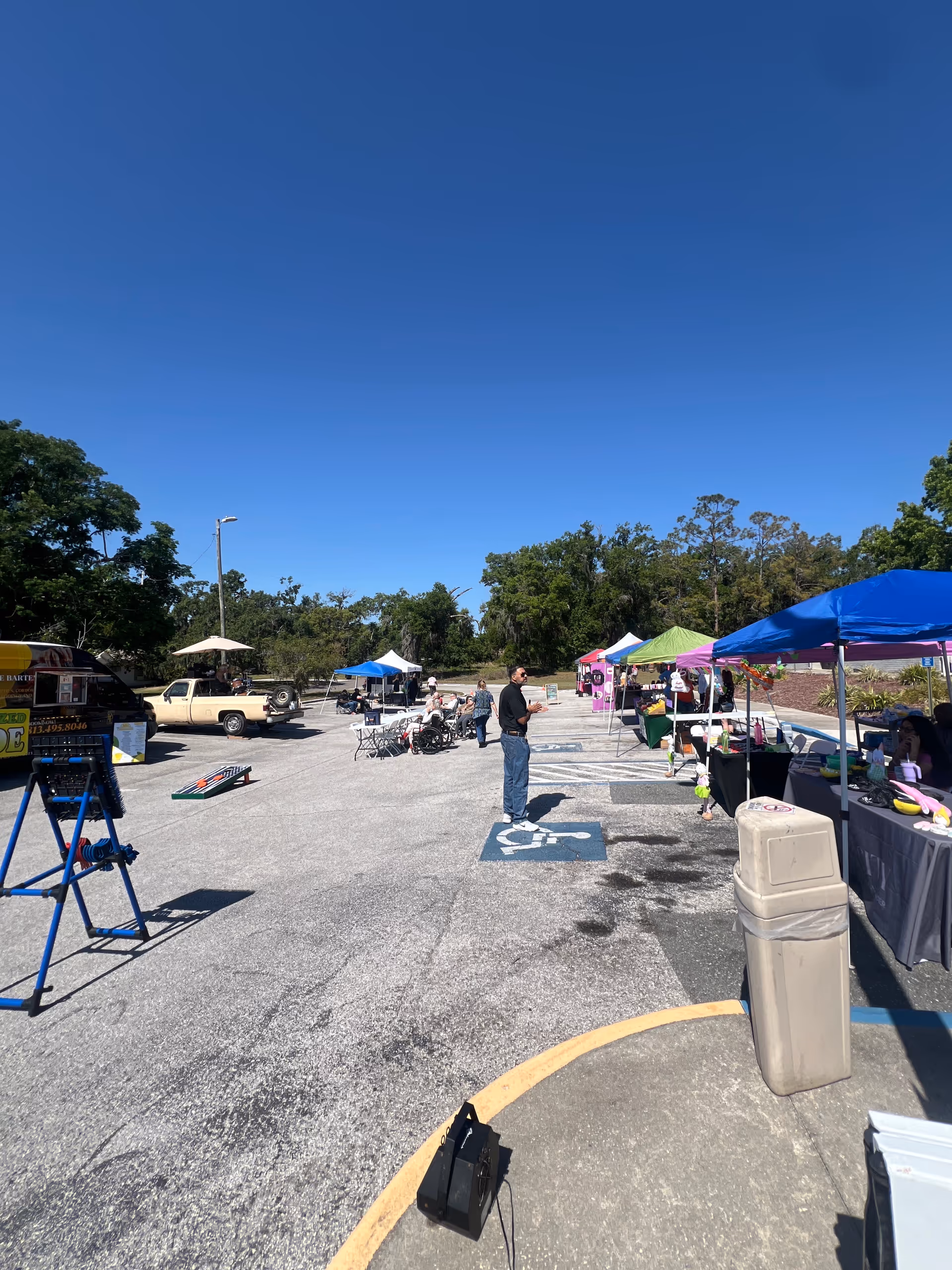 Outdoor parking lot at Heritage Park Health and Rehabilitation Center with colorful tents and people.