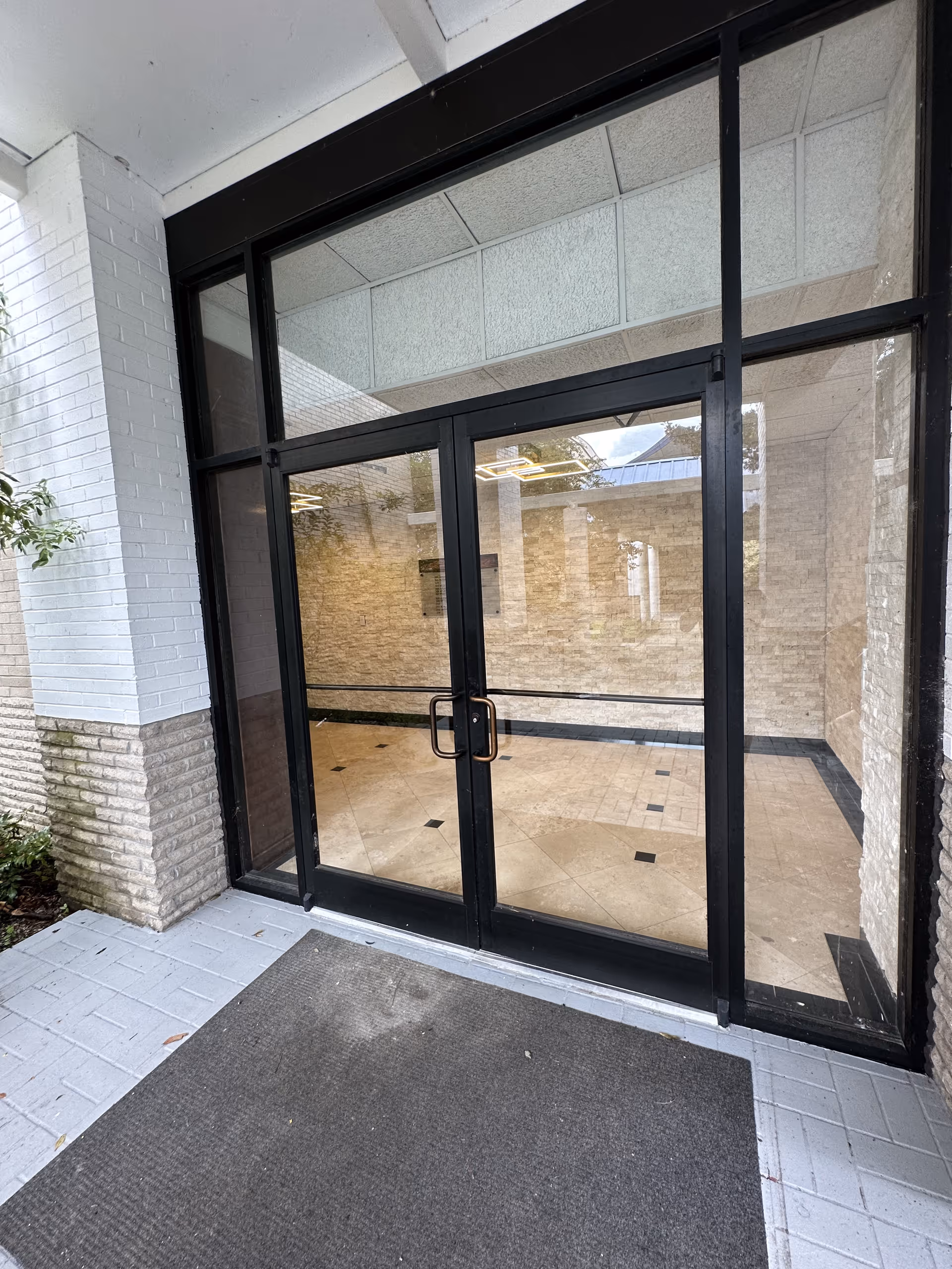 Glass front entrance doors with black frames and a tiled entryway.